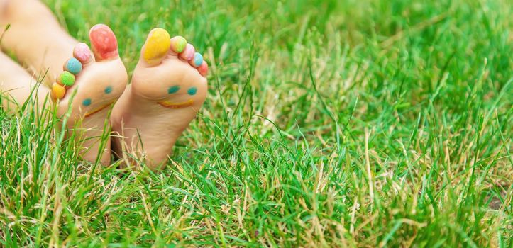 Children's feet with a pattern of paints smile on the green grass. Selective focus. nature.