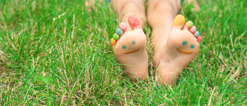 Children's feet with a pattern of paints smile on the green grass. Selective focus. nature.