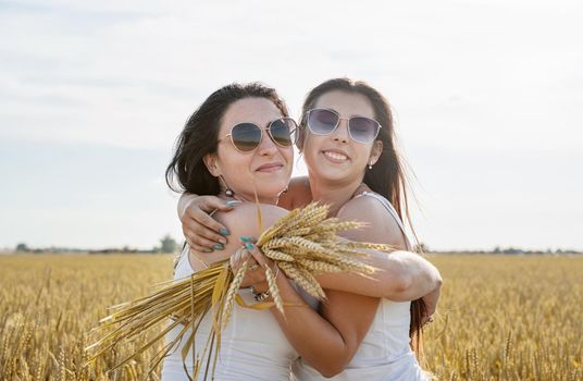 Freedom, friendship concept. Two smiling female friends in white shirts in the wheat field