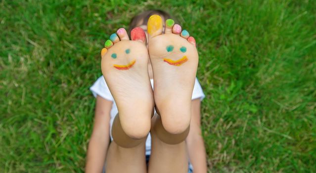 Children's feet with a pattern of paints smile on the green grass. Selective focus. nature.