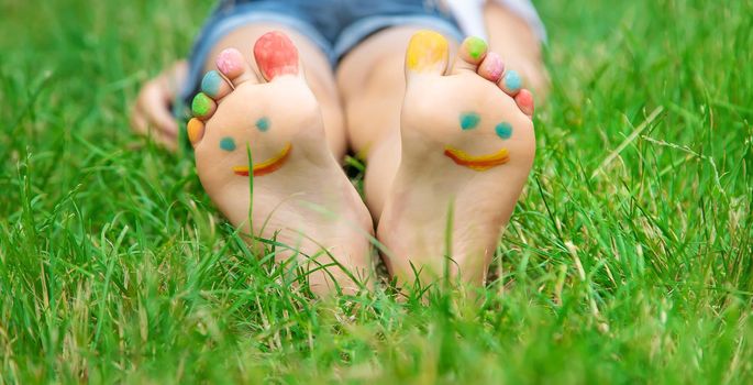 Children's feet with a pattern of paints smile on the green grass. Selective focus. nature.