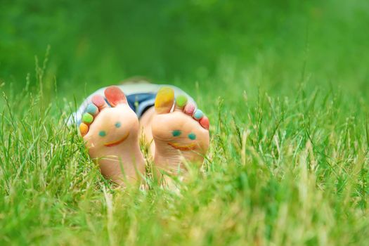 Children's feet with a pattern of paints smile on the green grass. Selective focus. nature.