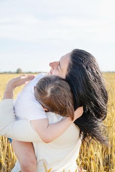 Happy family on a summer walk, mother and child walk in the wheat field and enjoy the beautiful nature, at sunset