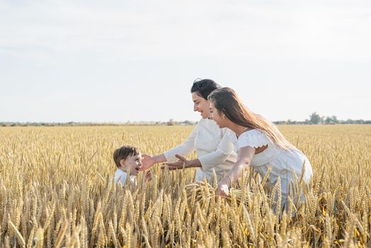 happy family of three people, mother and two children walking on wheat field