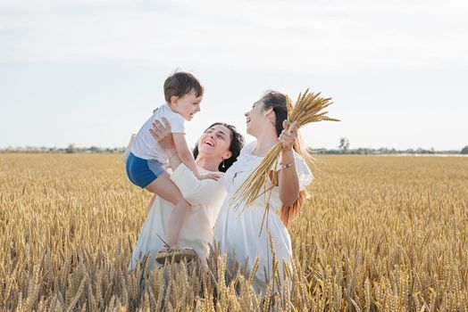 happy family of three people, mother and two children walking on wheat field