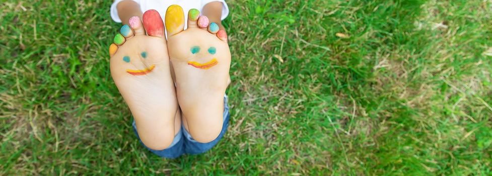 Children's feet with a pattern of paints smile on the green grass. Selective focus. nature.