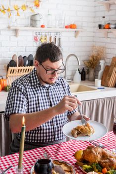 Happy Thanksgiving Day. Autumn feast. Woman and man celebrating holiday eating traditional dinner at kitchen with turkey, vegetables and pumpkin pie