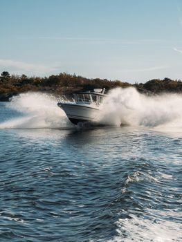 Fast motor boat in navigation goes on the waves in deep blue water, sea view. Speedboat off the coast of the island, high speed and splash