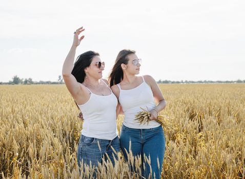 Freedom, friendship concept. Two smiling female friends in white shirts in the wheat field