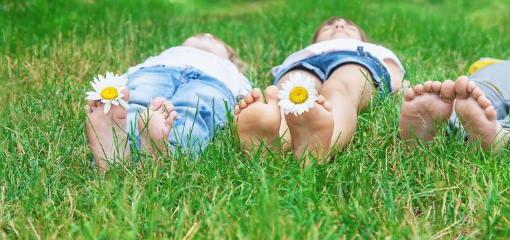 Children's feet with chamomile on green grass. Selective focus. nature.