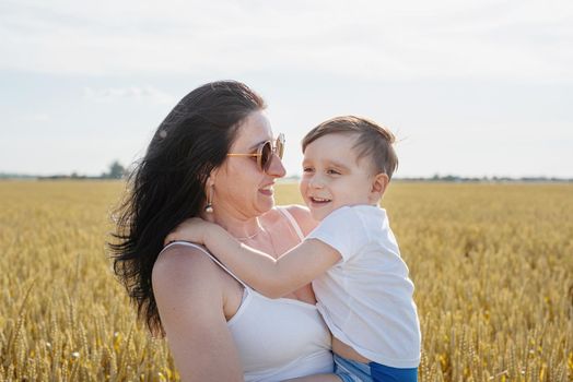 Happy family on a summer walk, mother and child walk in the wheat field and enjoy the beautiful nature, at sunset