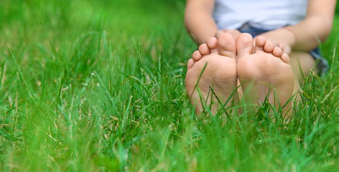 Children's feet on the green grass in the park. Selective focus. nature.