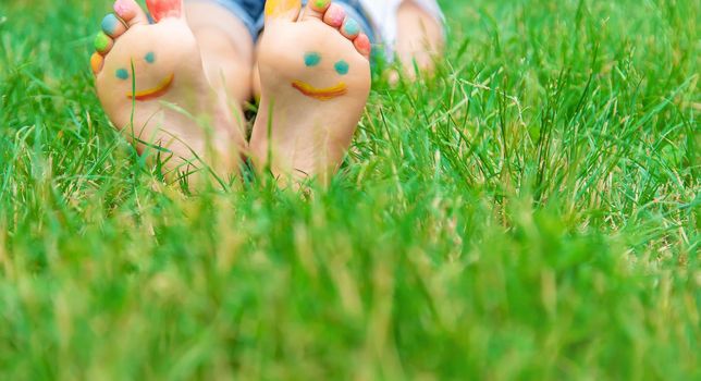 Children's feet with a pattern of paints smile on the green grass. Selective focus. nature.