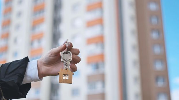 Girl holding keys to apartment against the backdrop of an apartment building