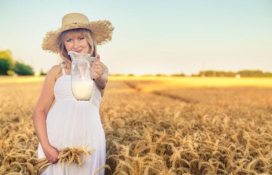 Pregnant woman in a wheat field with milk. Selective focus. nature.