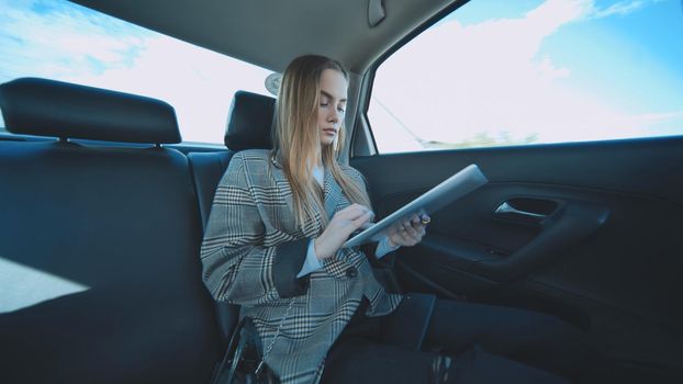 Busy student working with her tablet and phone in her car