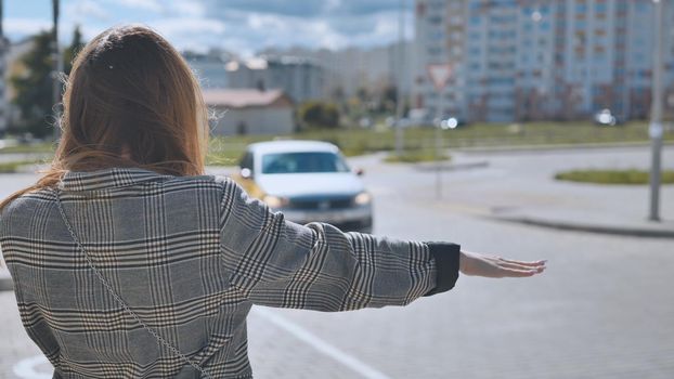 A girl is waving to a cab in the city