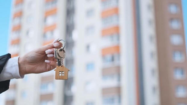 Girl holding keys to apartment against the backdrop of an apartment building