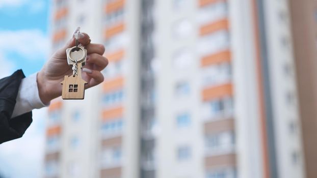 Girl holding keys to apartment against the backdrop of an apartment building
