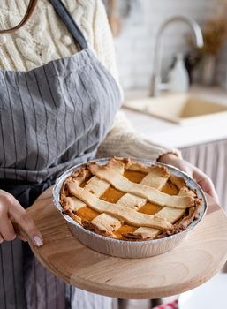 Happy Thanksgiving Day. Autumn feast. Woman celebrating holiday,closeup of a woman hands holding pumpkin pie at home kitchen