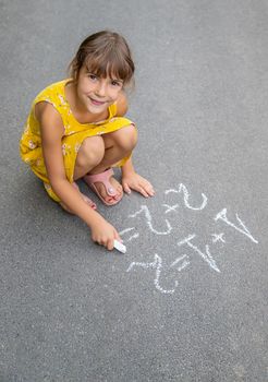 The child writes math on the pavement. Selective focus. summer.