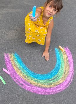 A child draws a rainbow on the asphalt. Selective focus. kid.