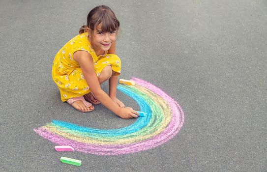 A child draws a rainbow on the asphalt. Selective focus. kid.