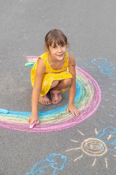 A child draws a rainbow on the asphalt. Selective focus. kid.