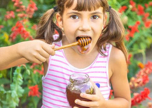 Child eats honey summer photo. Selective focus. nature.