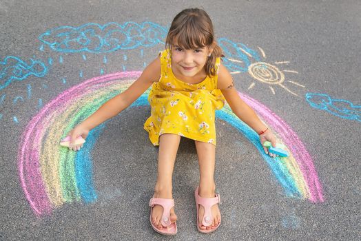 A child draws a rainbow on the asphalt. Selective focus. kid.