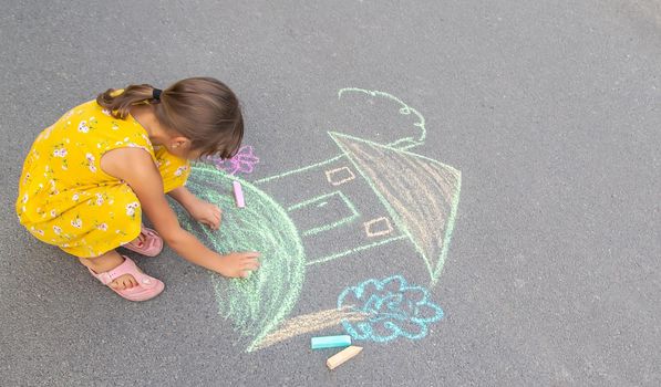 The child draws a house on the asphalt. Selective focus. kid.