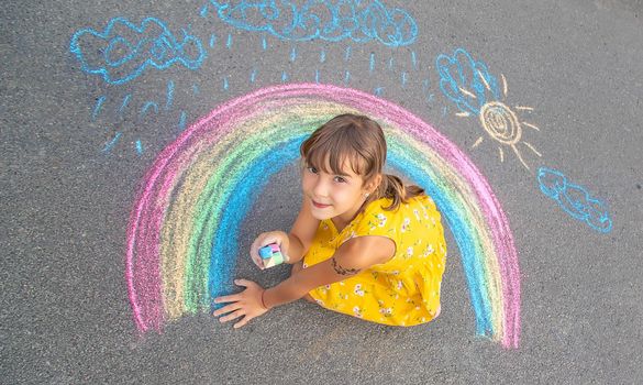 A child draws a rainbow on the asphalt. Selective focus. kid.