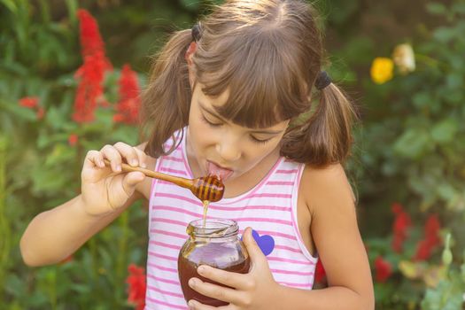 Child eats honey summer photo. Selective focus. nature.