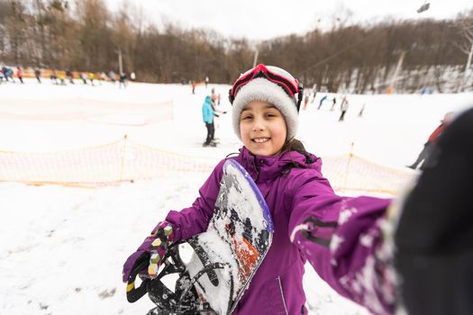 Little Cute Girl Snowboarding at ski resort in sunny winter day