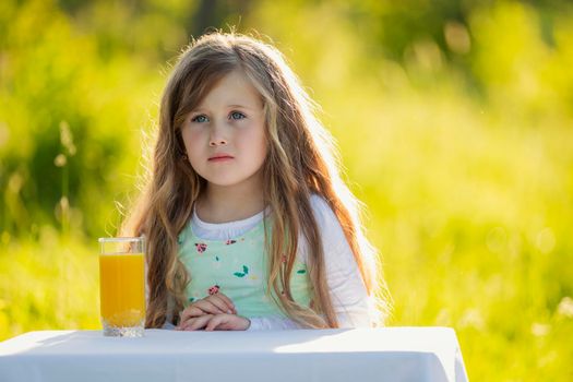 little girl in nature with a glass of orange juice