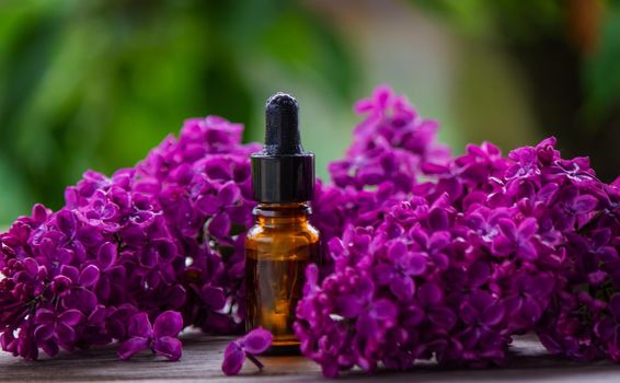 Lilac essential oil in a small bottle. Selective focus. Nature.