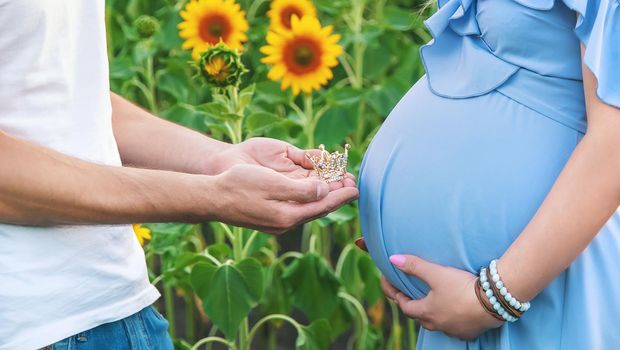 A pregnant woman and a man are holding a crown. Selective focus. nature.