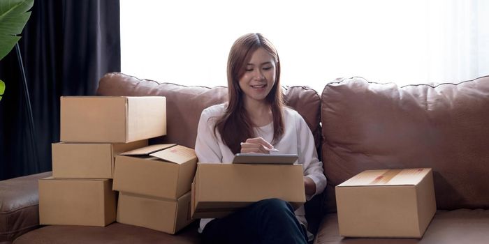 Starting small businesses SME owners female entrepreneurs Use a laptop or notebook to receive and review orders online to prepare to pack boxes, sell to customers, SME online business ideas..