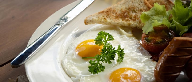 Close up fried eggs, roasted bacon, toasts, sausages and fresh salad for healthy breakfast.