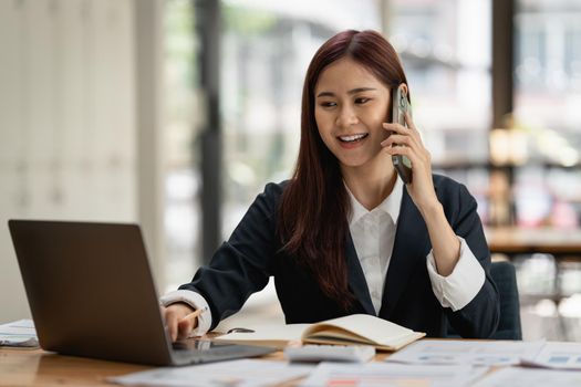 Image of Happy Asian Business woman discussing with her business partner by cell phone. Finance and brainstorm concept