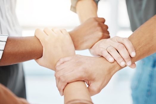 Closeup of diverse group of people holding each others wrists in a circle to express unity, support and solidarity. Connected hands of multiracial community linked for teamwork in a huddle. Society join together for collaboration and equality.