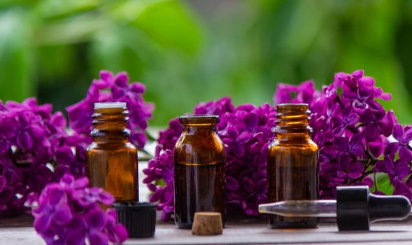 Lilac essential oil in a small bottle. Selective focus. Nature.