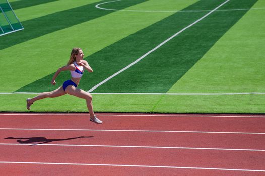 Young caucasian woman is engaged in jogging at the stadium outdoors