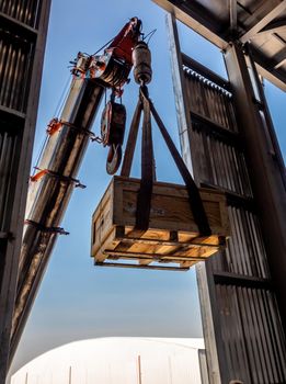 The crane carrying a wooden box of the radioactivity holder into the window on the factory floor