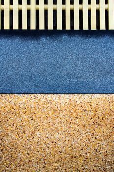 The different surface texture on joint of the exposed aggregate finish flooring and the marble remnants finish flooring and the plastic gutter cover beside the pool