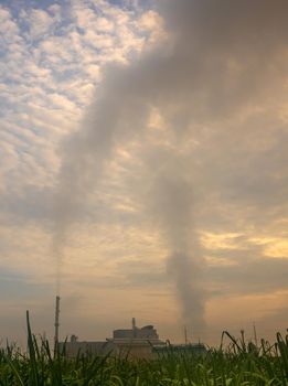 Smoke from the boiler and the steam from the cooling tower in the power plant. It is located in the middle of an agricultural area