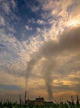 Smoke from the boiler and the steam from the cooling tower in the power plant. It is located in the middle of an agricultural area