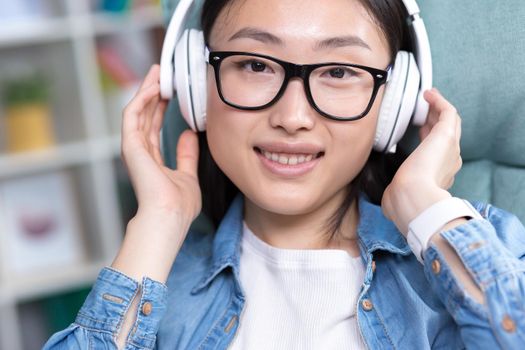 Portrait of a young Asian teenage girl listening to music in white headphones photo close up portrait.
