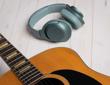 Music recording scene with guitar, empty music sheet, pencil and headphones on white wooden table