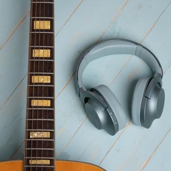 view from above of guitar and green headphones on wooden background, closeup